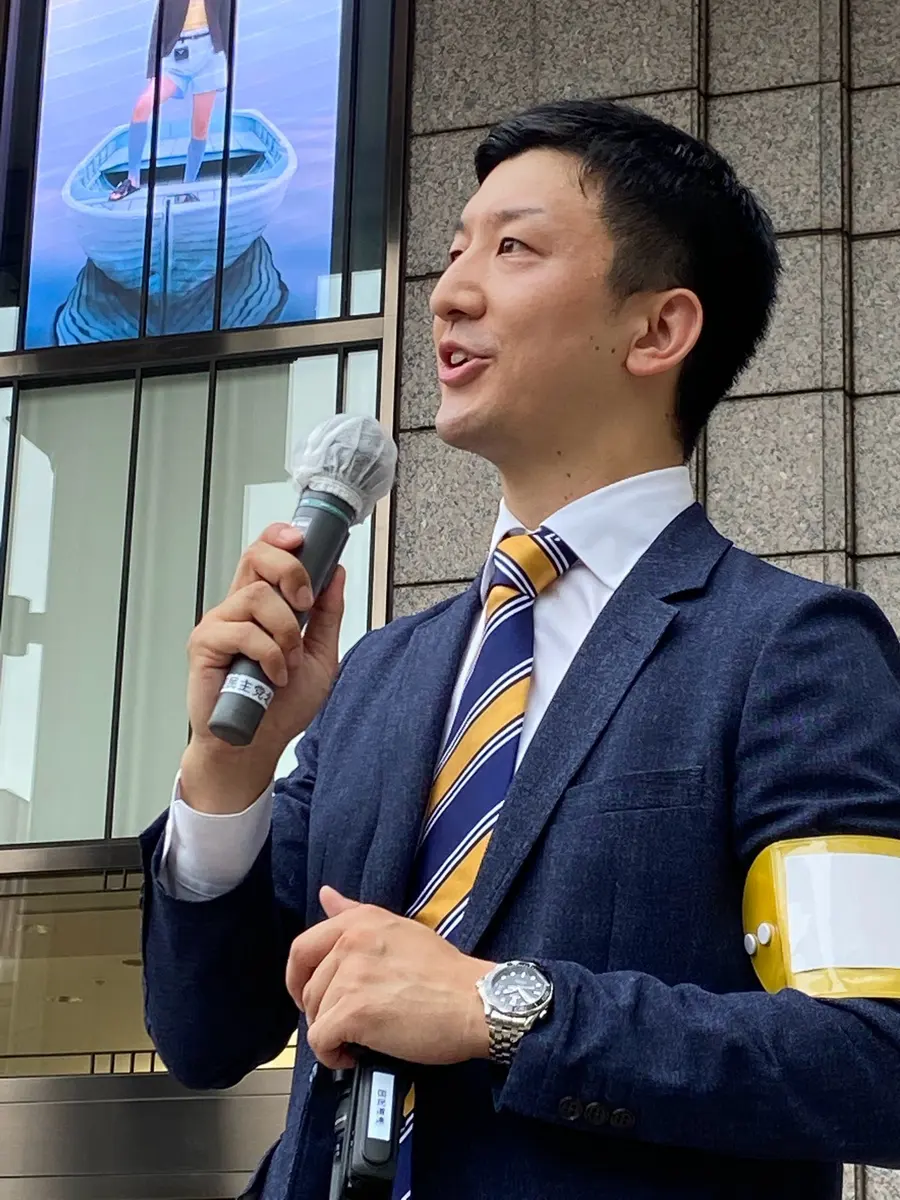 街頭でマイクを握り遠くを見て話す阿部恭介