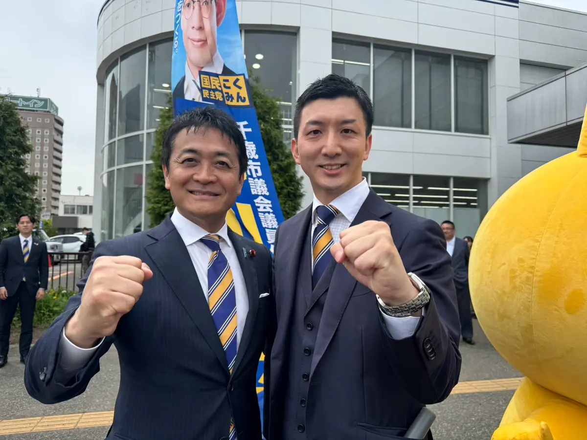 党の議員と並んで拳を上げる阿部恭介