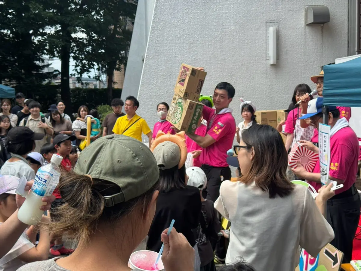 夏まつりの会場で来場者に景品を渡す場面