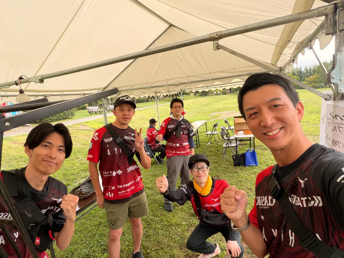 地域のお祭りのテントで仲間と並ぶ阿部恭介